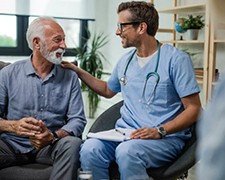 Male nurse sitting with a senior male patient having a good talk